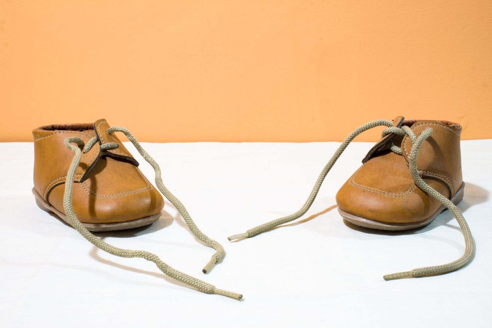 A pair of small brown leather baby shoes on a white table