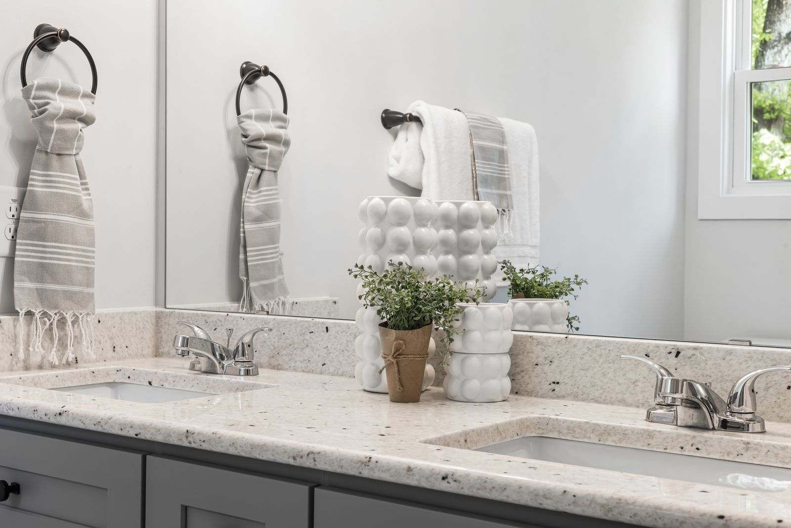 A bright bathroom with folded towels beside two sinks