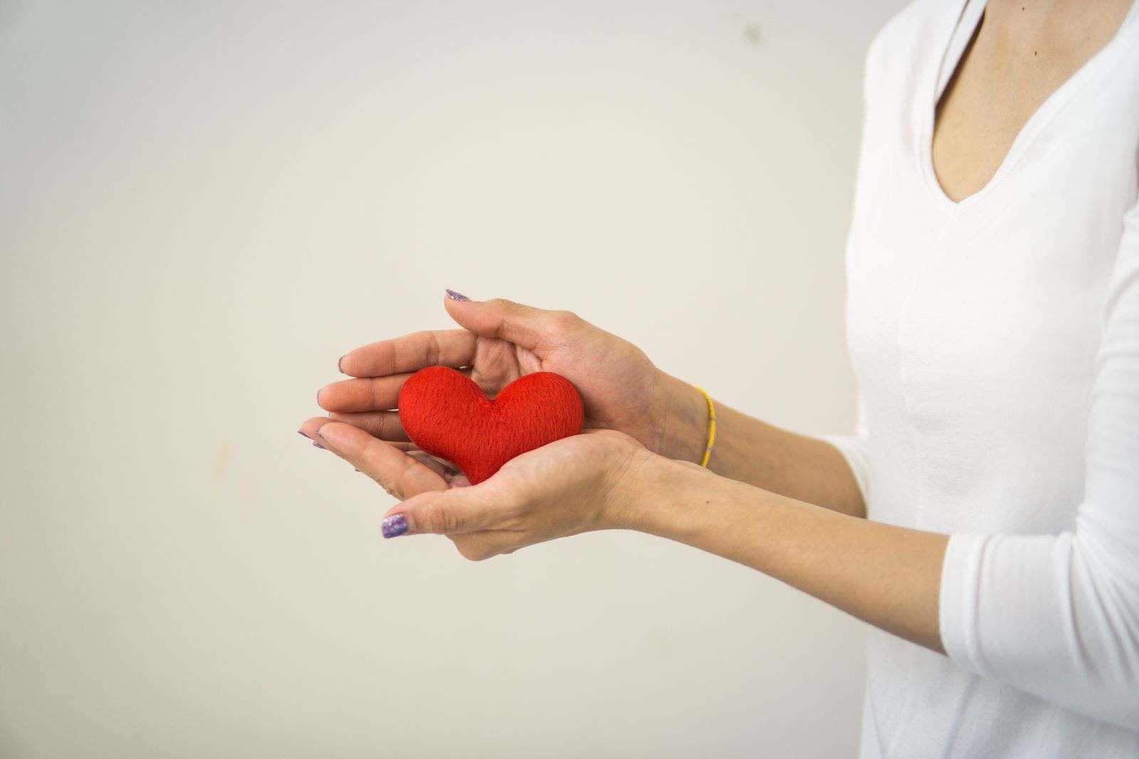 Open hands holding a small red felt heart