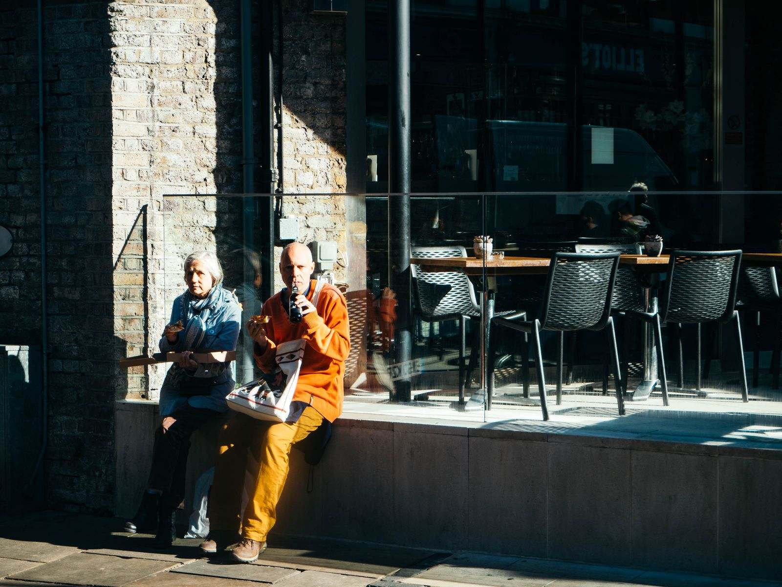 A mature couple sharing a moment outside a city cafe on a sunny day