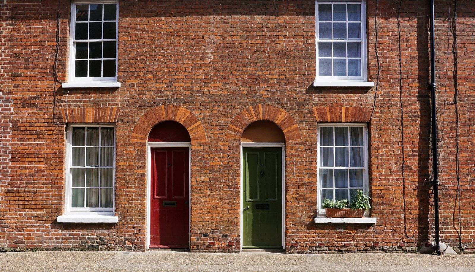 A red door and a green door side by side in a brick wall