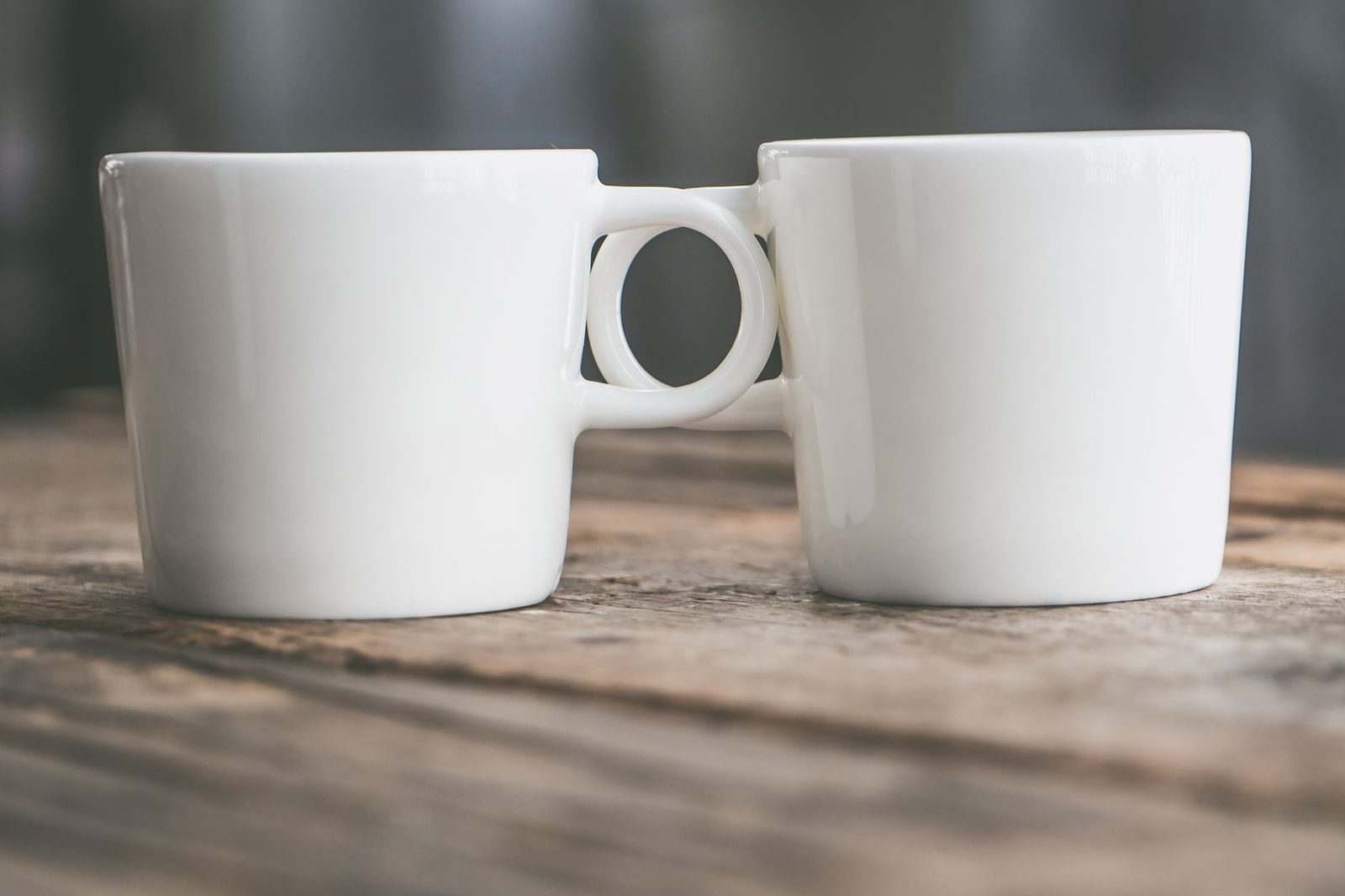 Two white mugs side by side on a wooden table