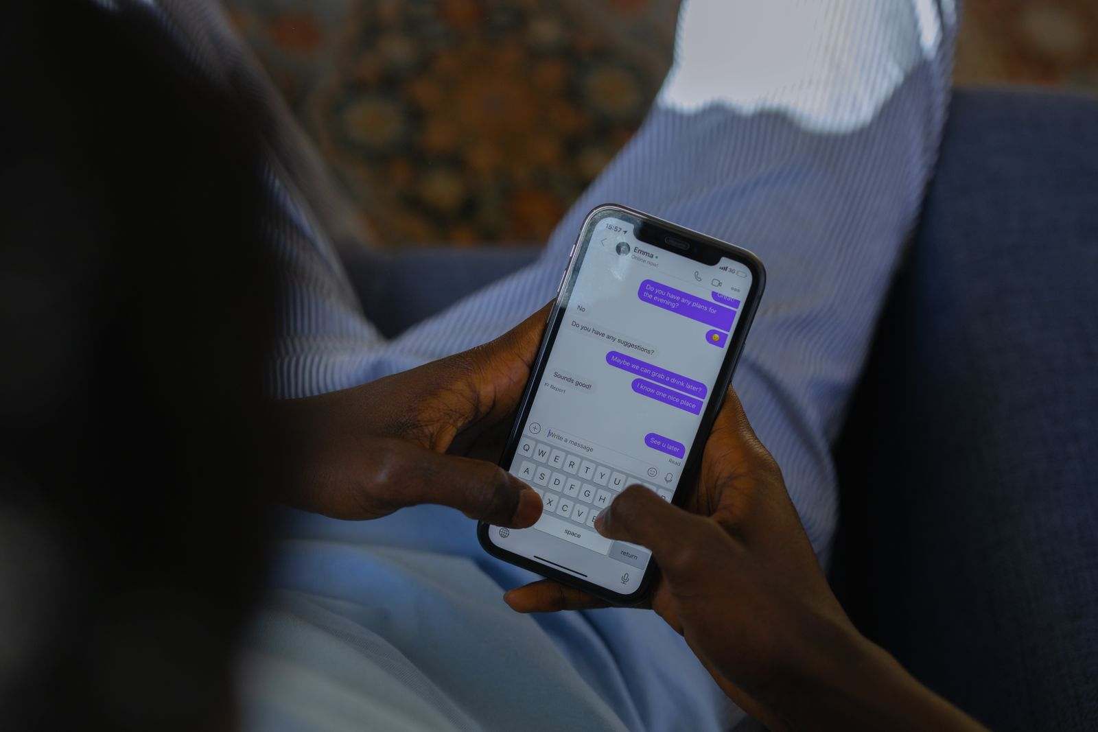 Hands typing a message on a phone on the couch